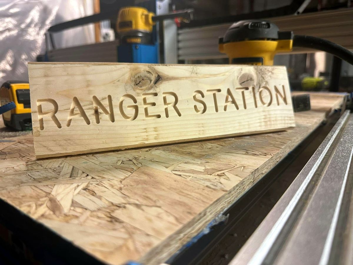 Wooden Ranger Station sign with carved letters sitting on the CNC machine in our shop