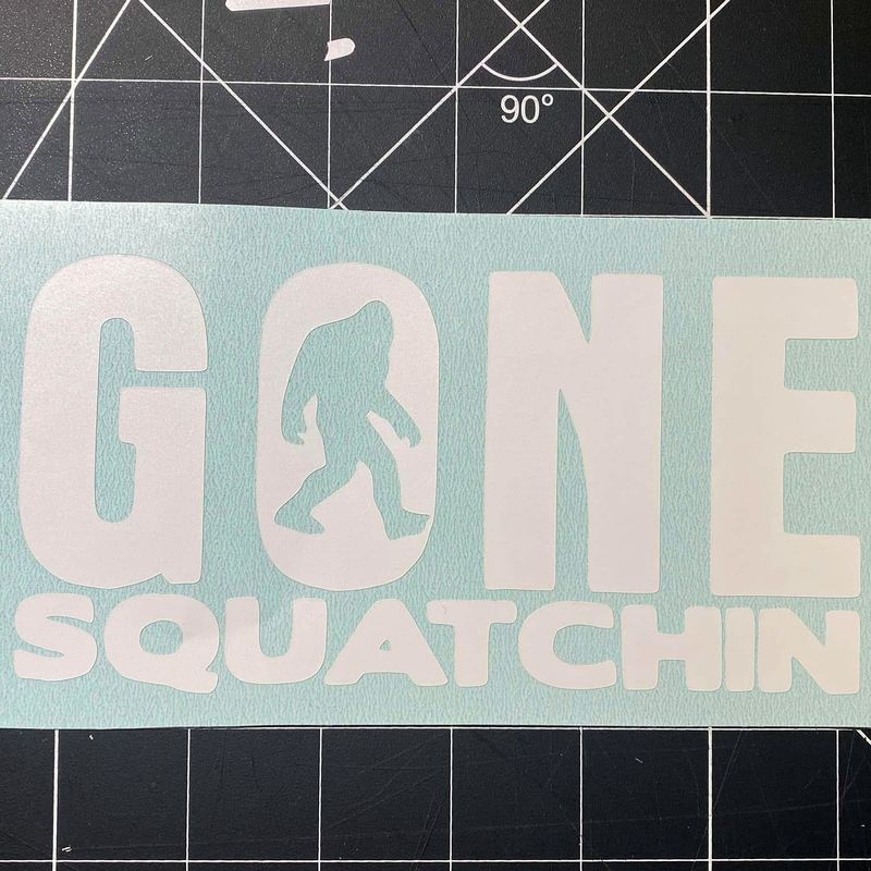 White cut vinyl Gone Squatchin decal with a Bigfoot silhouette on a cutting mat